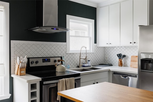 kitchen featuring stainless steel appliances, wall chimney exhaust hood, light countertops, and a sink