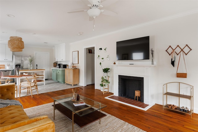 living area with wood finished floors, baseboards, and ornamental molding