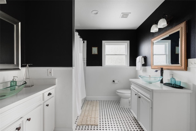 bathroom featuring vanity, toilet, baseboards, and visible vents