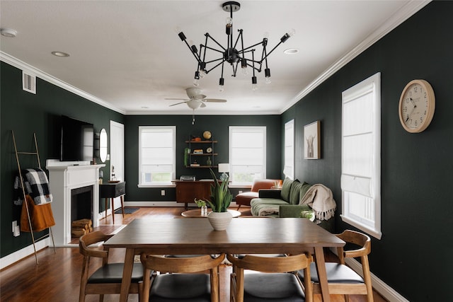 dining space featuring wood finished floors, baseboards, visible vents, a fireplace with flush hearth, and ornamental molding