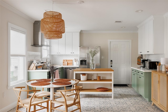 kitchen with visible vents, ornamental molding, plenty of natural light, wall chimney exhaust hood, and green cabinetry