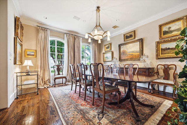 dining area with dark wood-style floors, visible vents, an inviting chandelier, and ornamental molding