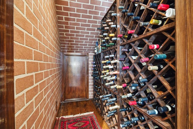 wine area featuring brick wall and wood finished floors