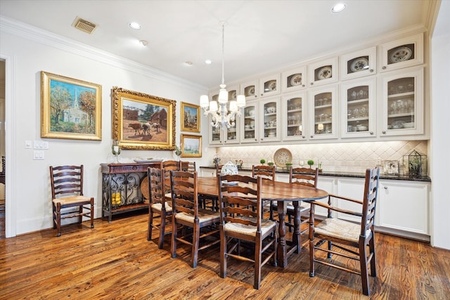 dining area featuring crown molding, wood finished floors, and visible vents