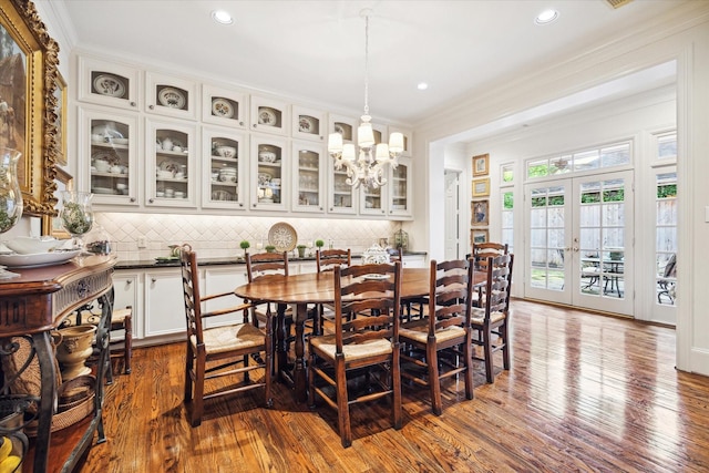 dining space with dark wood-style flooring, recessed lighting, french doors, and ornamental molding