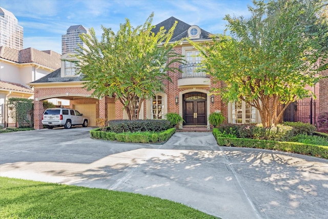 view of front of property featuring brick siding, a balcony, and driveway