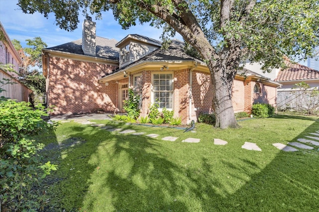 view of front of property with a front lawn, fence, brick siding, and a chimney