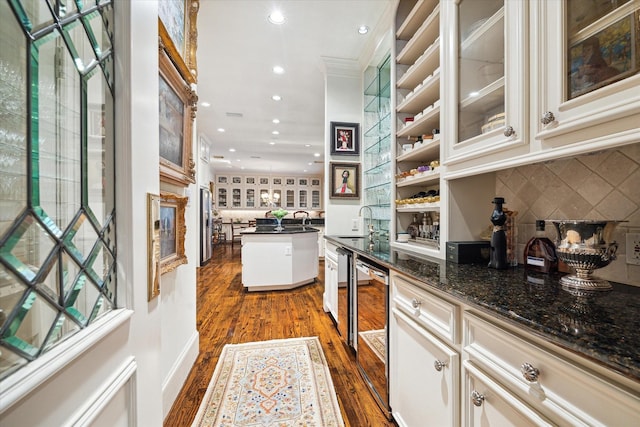 bar featuring dark wood finished floors, recessed lighting, ornamental molding, a sink, and tasteful backsplash