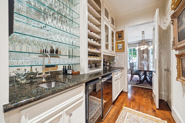 bar featuring light wood finished floors, beverage cooler, ornamental molding, wet bar, and a sink