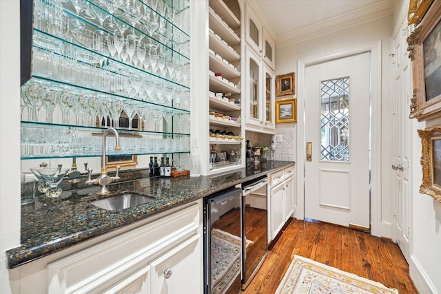 bar with beverage cooler, a sink, wood finished floors, crown molding, and wet bar