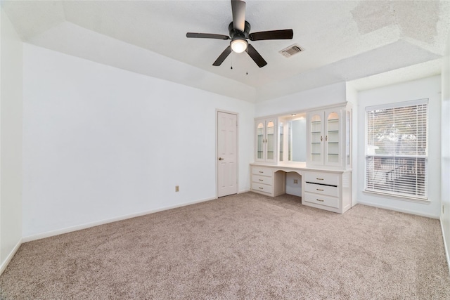 unfurnished bedroom with visible vents, baseboards, light colored carpet, and built in desk