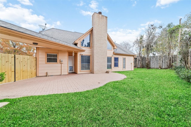 back of house with roof with shingles, a lawn, a chimney, a fenced backyard, and a patio