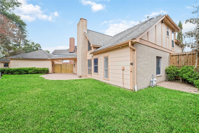 back of property featuring fence, a yard, brick siding, a chimney, and a patio area