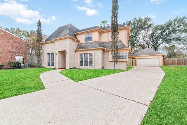 view of front of house featuring brick siding, a detached garage, a front yard, and fence