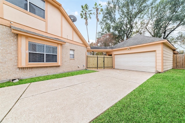 exterior space featuring brick siding, a lawn, a detached garage, and fence