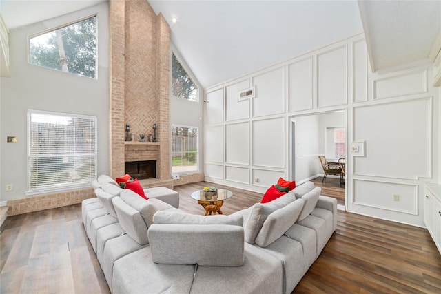 living room featuring dark wood-style floors, a decorative wall, plenty of natural light, and a large fireplace