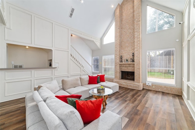 living room featuring stairway, a brick fireplace, a decorative wall, and wood finished floors