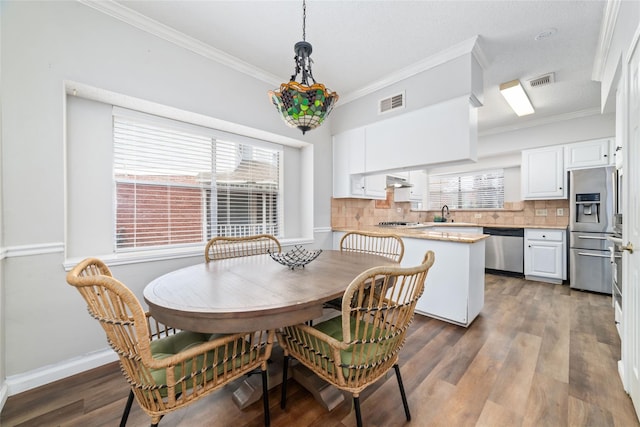 dining area featuring visible vents, baseboards, wood finished floors, and ornamental molding