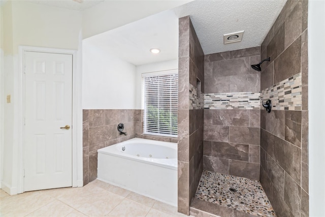 bathroom featuring tile patterned floors, a textured ceiling, tile walls, tiled shower, and a whirlpool tub