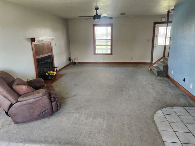 unfurnished living room featuring stairway, plenty of natural light, a fireplace, and carpet floors