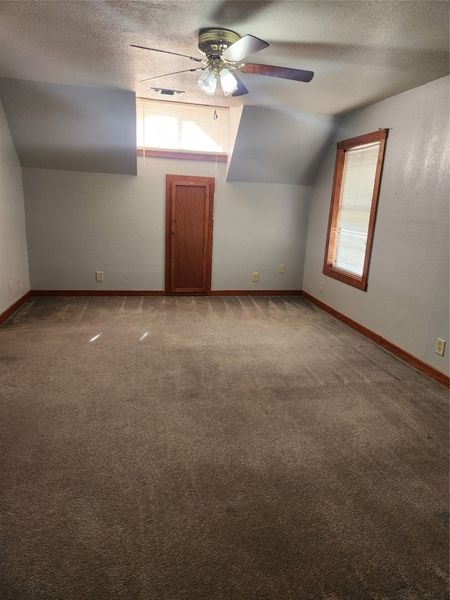 additional living space featuring a ceiling fan, lofted ceiling, carpet, and a textured ceiling