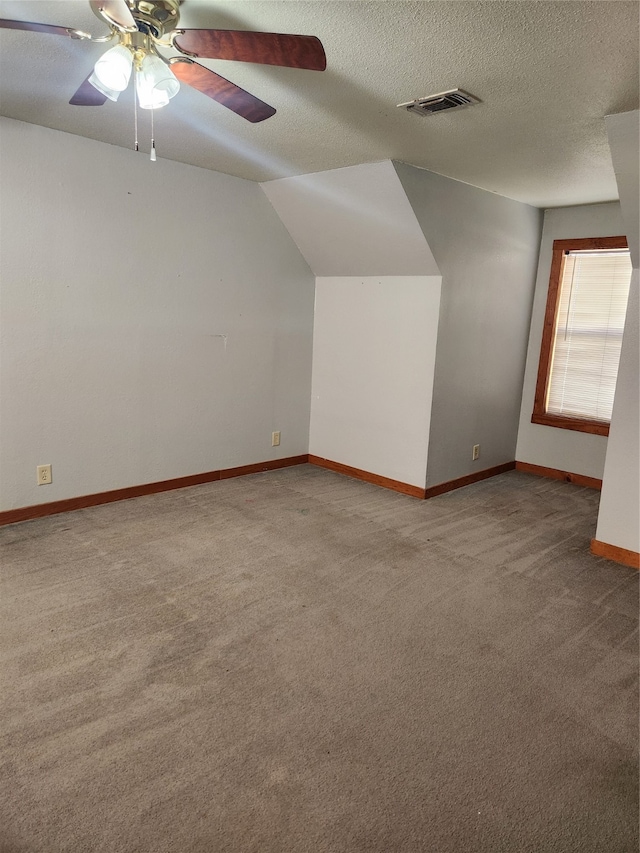 additional living space featuring a textured ceiling, visible vents, carpet floors, and ceiling fan