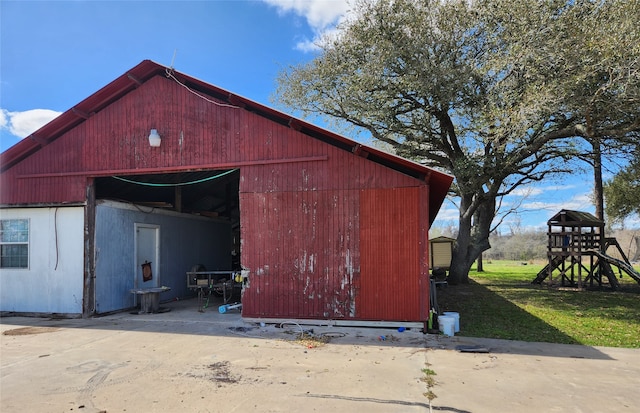 view of pole building with a yard, concrete driveway, and a playground