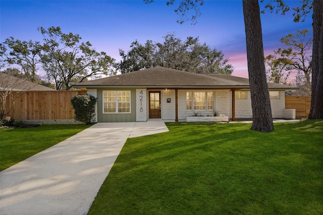 view of front of home featuring a front yard, concrete driveway, fence, and roof with shingles