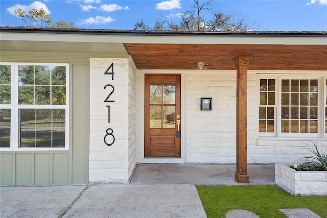 view of exterior entry with concrete block siding and covered porch