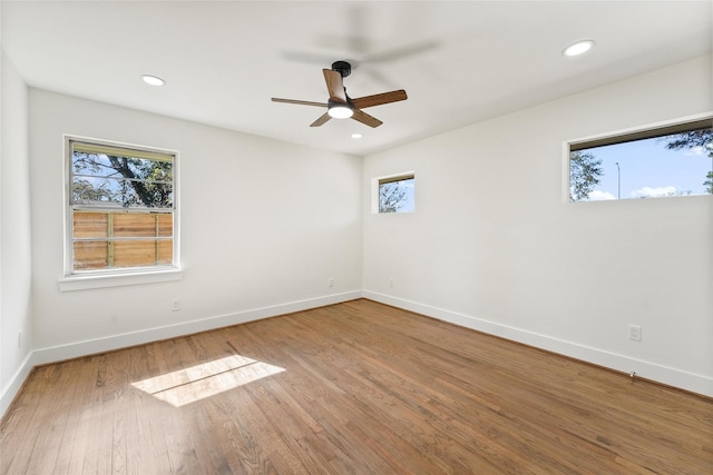 empty room with wood finished floors, recessed lighting, a ceiling fan, and baseboards