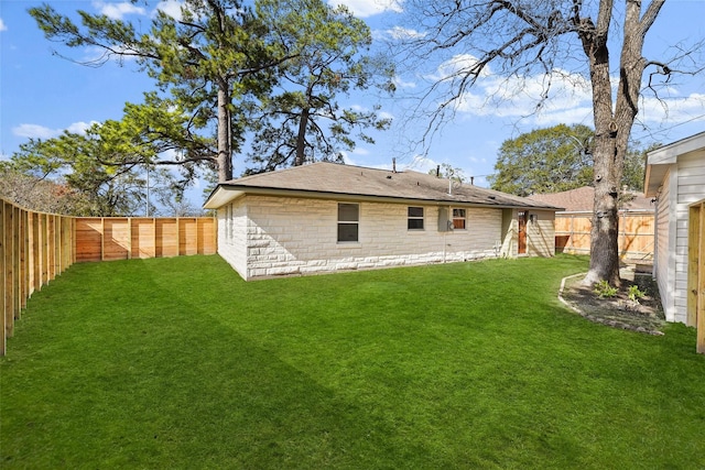 rear view of property with a yard and a fenced backyard