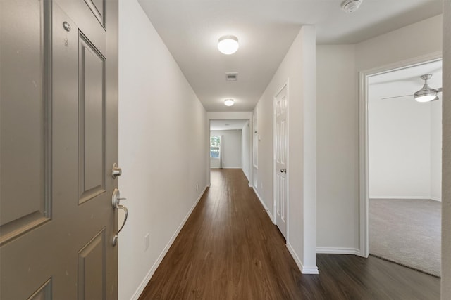 hall with baseboards, visible vents, and dark wood-style flooring