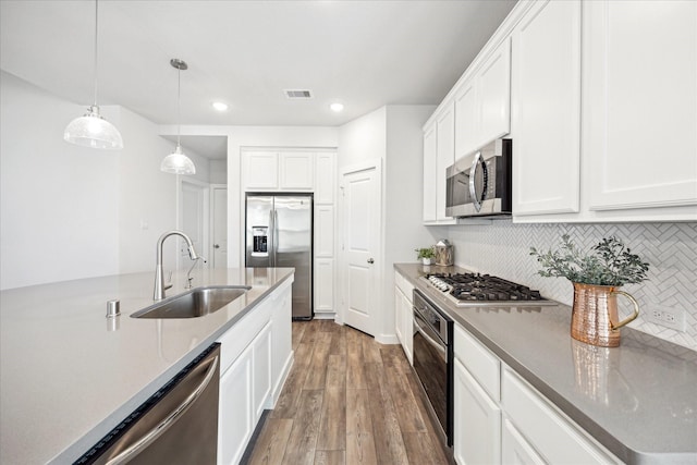 kitchen with wood finished floors, visible vents, a sink, appliances with stainless steel finishes, and tasteful backsplash