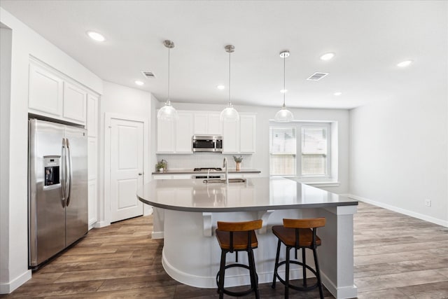 kitchen with visible vents, appliances with stainless steel finishes, decorative backsplash, and dark wood-style flooring