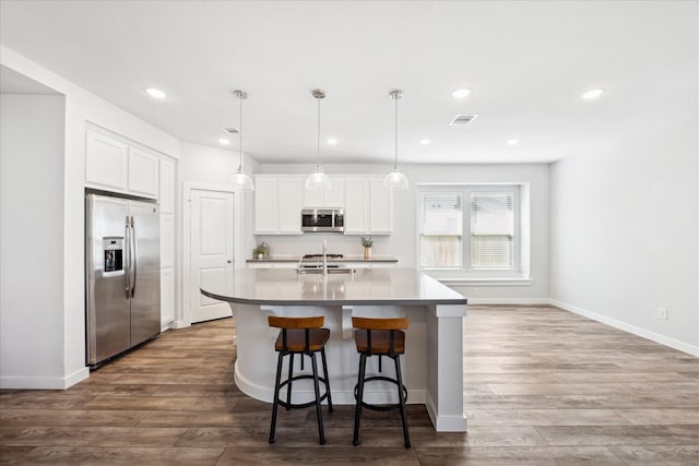 kitchen with visible vents, an island with sink, dark wood-style flooring, appliances with stainless steel finishes, and white cabinetry