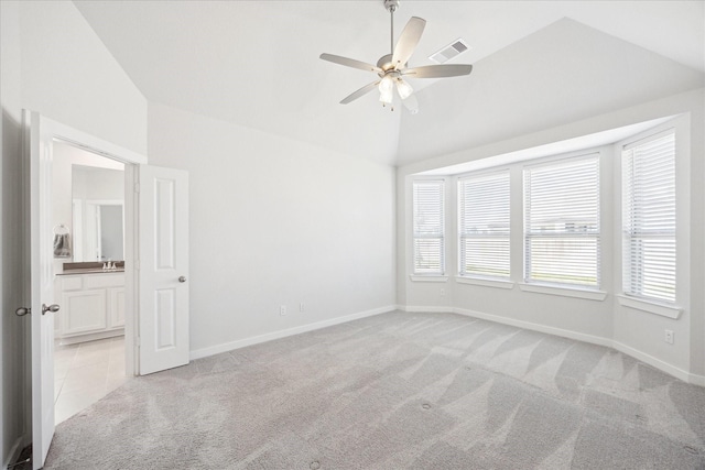 spare room with visible vents, ceiling fan, baseboards, light colored carpet, and vaulted ceiling