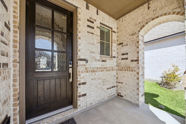 property entrance with a porch and brick siding