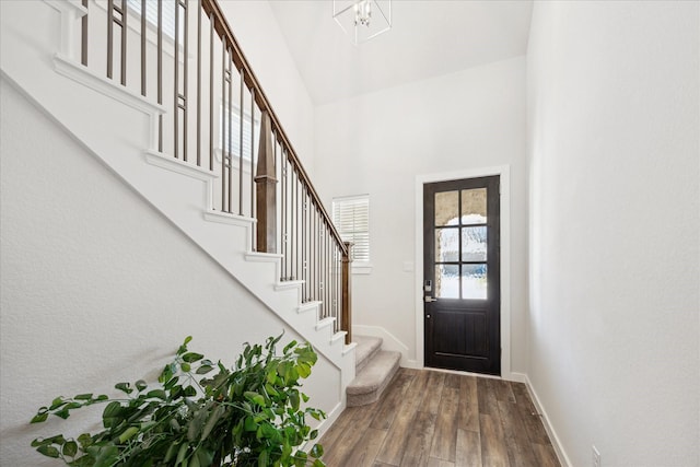 entrance foyer with stairway, wood finished floors, baseboards, and a towering ceiling