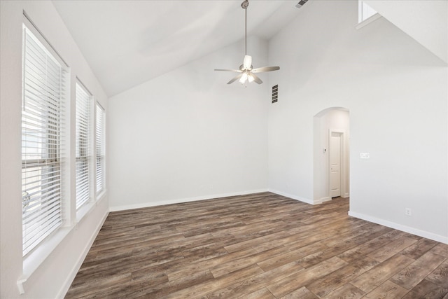 empty room with baseboards, arched walkways, wood finished floors, and a ceiling fan