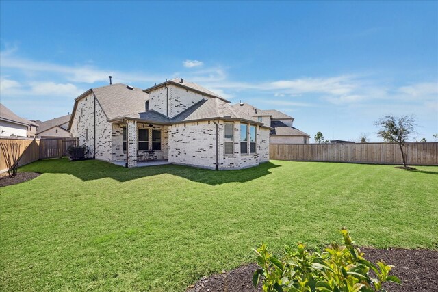 back of property with brick siding, a lawn, a fenced backyard, and a ceiling fan