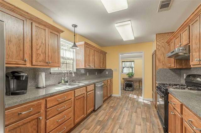 kitchen featuring visible vents, under cabinet range hood, dishwasher, black range with gas cooktop, and a sink