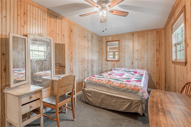 carpeted bedroom with multiple windows, wooden walls, and ceiling fan