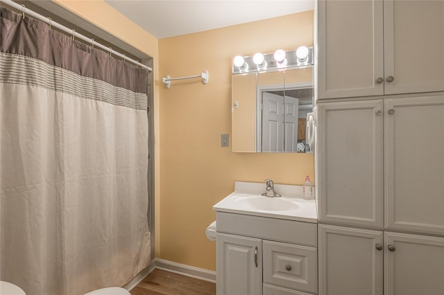 bathroom with baseboards, toilet, a shower with shower curtain, wood finished floors, and vanity