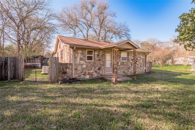 exterior space with stone siding, a front yard, and fence