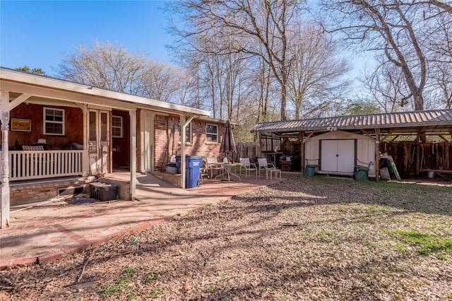 view of yard featuring an outbuilding, fence, a shed, covered porch, and a patio area