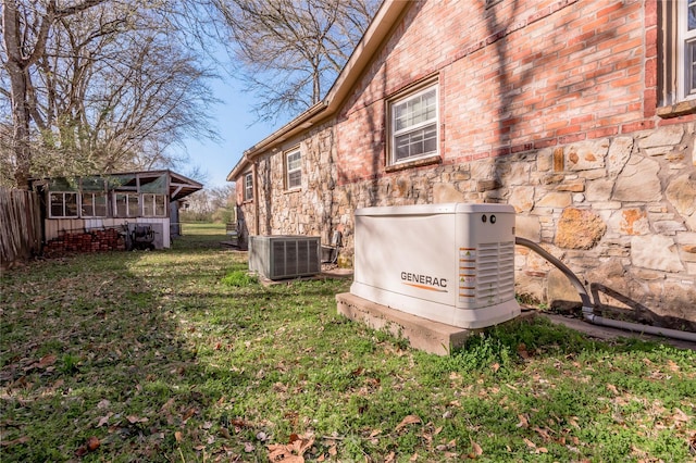 details with stone siding, a power unit, central AC, and fence