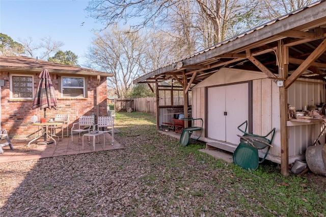 view of yard with a storage shed, an outbuilding, fence, and a patio area