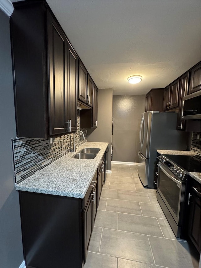 kitchen with dark brown cabinetry, backsplash, stainless steel appliances, and a sink