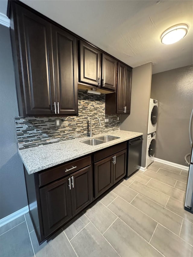 kitchen with a sink, black dishwasher, dark brown cabinets, stacked washer / dryer, and tasteful backsplash