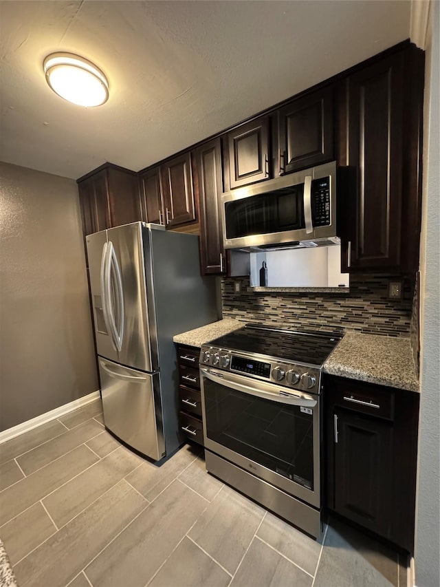 kitchen featuring wood finish floors, tasteful backsplash, stainless steel appliances, baseboards, and light stone countertops